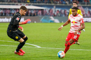 Borussia Dortmund's Gregor Kobel attempts to stop RB Leipzig's Christopher Nkunku